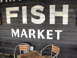 Fish Market sign and cafe tables in Whitstable Harbour