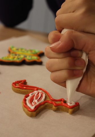 Child icing a flamingo shaped biscuit with pink and white icing during a class