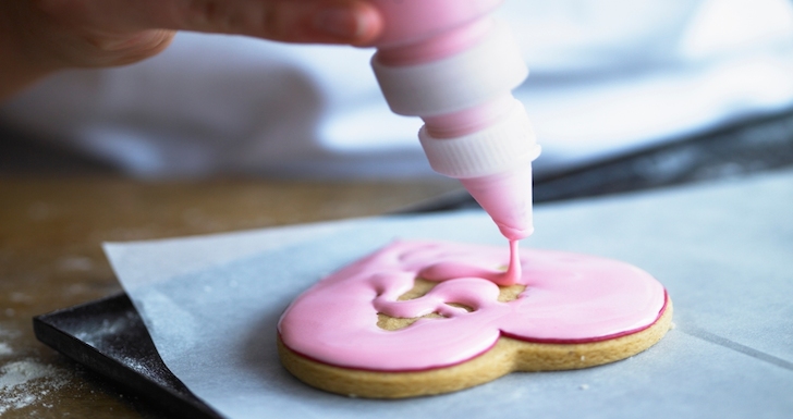 Person Icing a pink heart biscuit at Biscuiteers class London