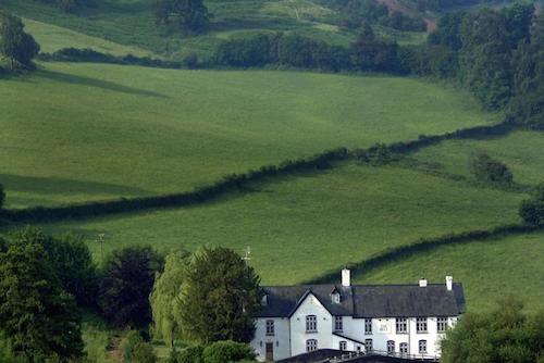 The Bell at Skenfrith pub surrounded by green fields and trees
