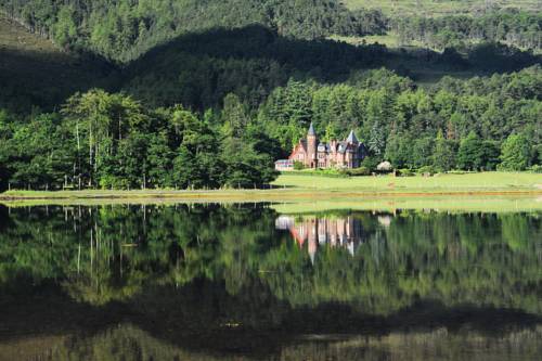 Torridon Hotel surrounded by forest and with Torridon Loch in the foreground