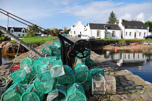 White washed Eilean Iarmain hotel with lobster pots in foreground