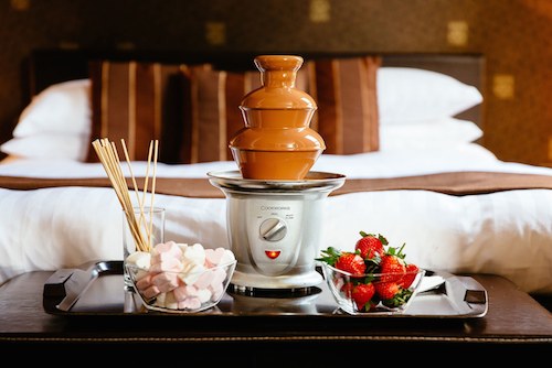 Chocolate fountain with bowls of strawberries and marshmallows in chocolate themed bedroom