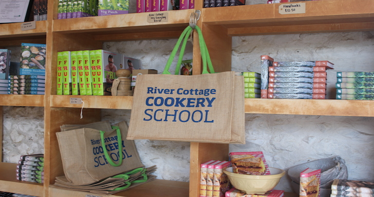 Shelves displaying River Cottage Cookery School bags and series of cook books